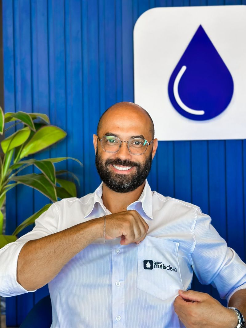 Gestor do Grupo Mais Clean mostrando o bordado da camisa, na sede