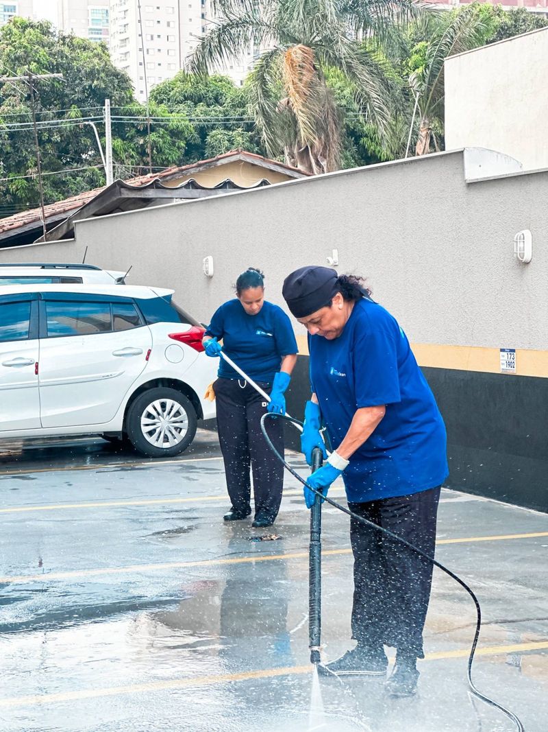 Duas colaboradoras lavando o piso da garagem de um condomínio com lavadora de alta pressão